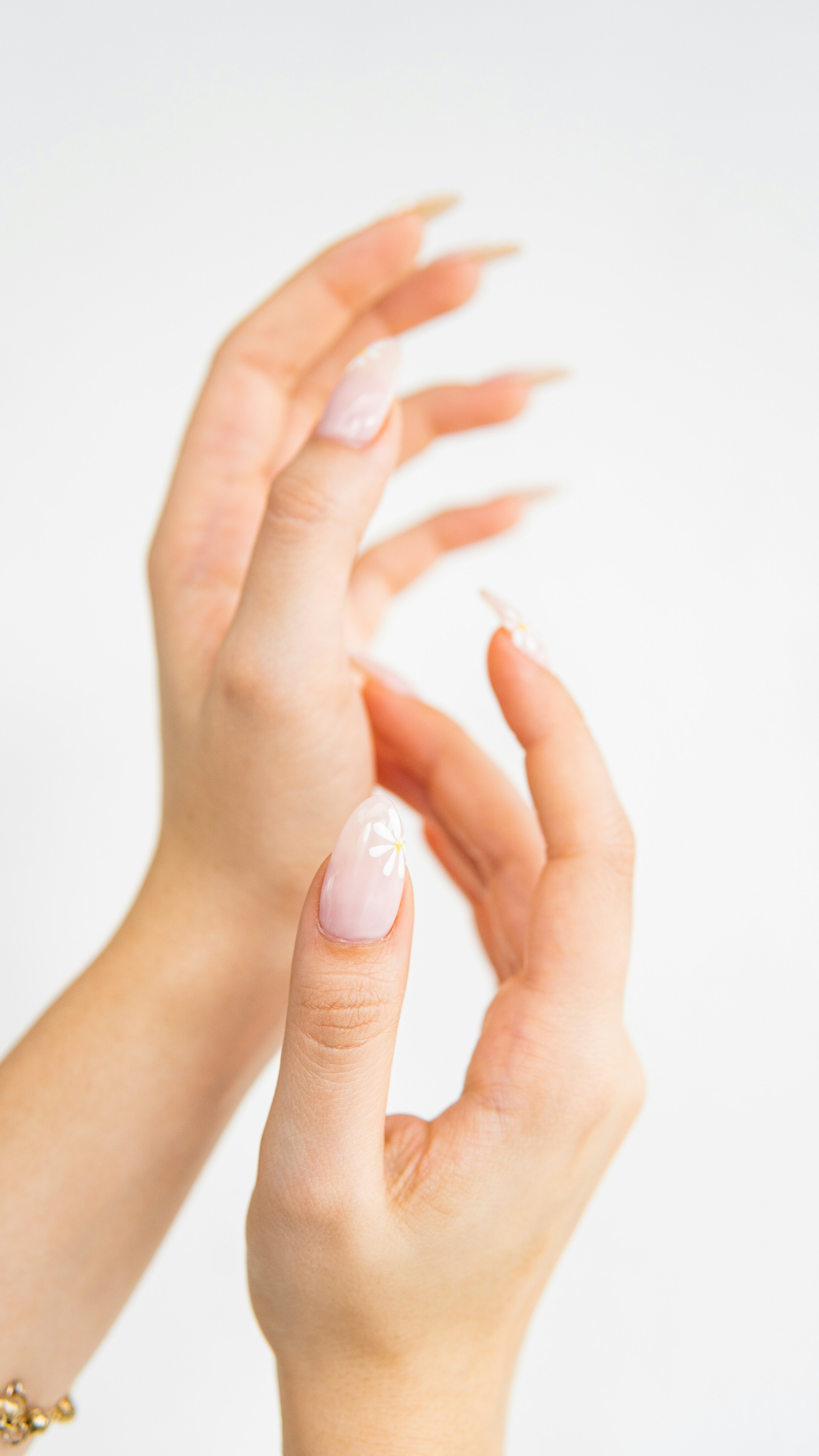 Hands-only placeholder of soft floral nail art on a white backdrop